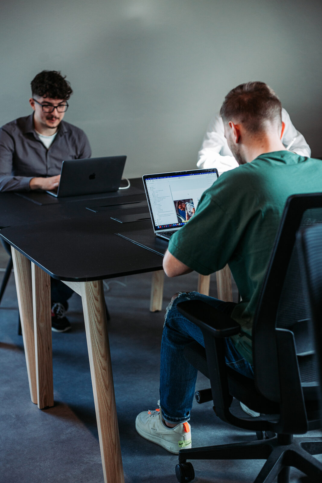 Zwei Designer im konzentrierten Deep-Work an einem schwarzen Tisch