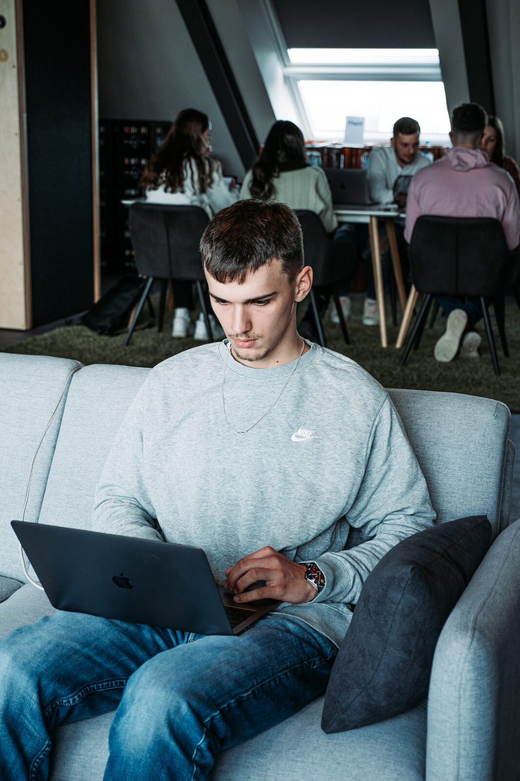 Designer arbeitet konzentriert mit Laptop in der hellen Loft-Etage der Greenstein Designagentur